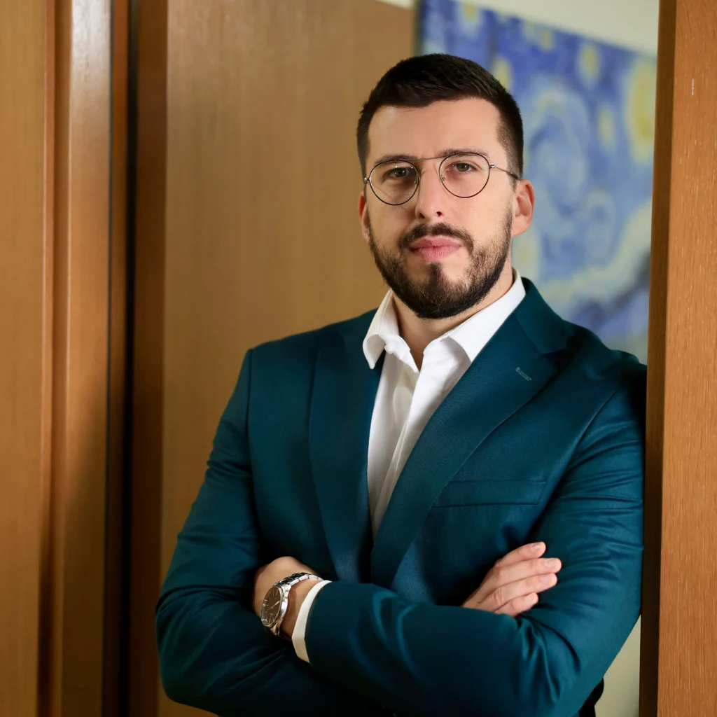 Advokat Nenad Vladić osnivać advokatske kancelarije Vladić iz Beograda naslonjen na vrata sa prekrštenim rukama.